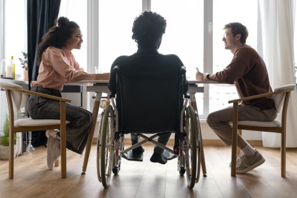 Personne en fauteuil roulant autour d'une table avec des amis